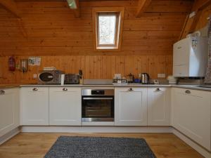 uma cozinha com armários brancos e uma janela em Chalet Rowan Cottage by Interhome em Inverness