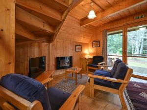 a log cabin living room with a fireplace and a tv at Chalet Rowan Cottage by Interhome in Inverness