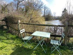 two chairs and a table next to a fence and a river at Rural Retreat in Idyllic Countryside - fishing & walks in Hawkhurst