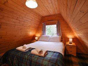 um quarto com uma cama num chalé de madeira em Chalet Rowan Cottage by Interhome em Inverness