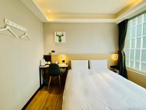 a hotel room with a bed and a desk at Hub Hotel Songshan Inn in Taipei