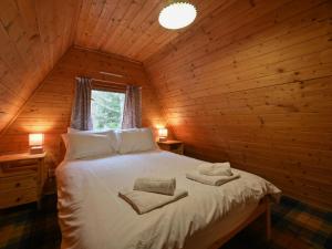 um quarto com uma cama num chalé de madeira em Chalet Birchwood Cottage by Interhome em Inverness