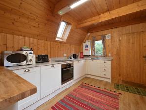 a kitchen with white appliances and wooden walls at Chalet Birchwood Cottage by Interhome in Inverness