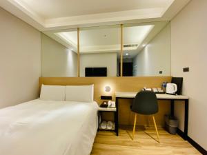 1 dormitorio con cama, escritorio y espejo en Hub Hotel Songshan Inn en Taipéi