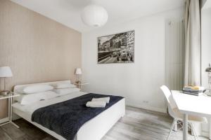 een witte slaapkamer met een bed en een bureau bij Warsaw Night Apartments Menica Residence in Warschau