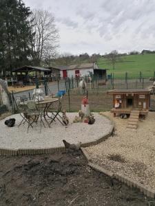 a playground with a picnic table and chickens in the dirt at le gite de zoelie in Chaineux