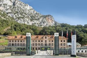 a large building with a mountain in the background at Hotel Balneario La Hermida in La Hermida