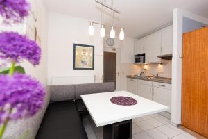 uma pequena cozinha com uma mesa branca e flores roxas em Trafalgar 349 em Döse