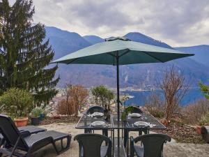 a table with a green umbrella and chairs with a view at Holiday Home Casa Pina by Interhome in Porlezza