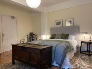 um quarto com uma cama com um baú de madeira ao lado de uma mesa em Riverfront Apartments at The Blue Goat Ramelton em Ramelton