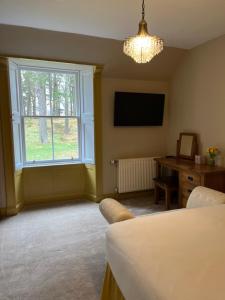 a living room with a bed and a tv and a window at The Farmhouse B&B in Dunkeld