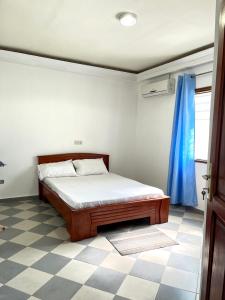 1 dormitorio con cama y cortina azul en Villa meublée Cotonou fidjrosse 05 min de la plage, en Cotonou
