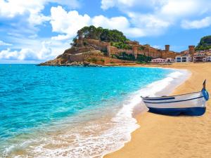 a boat on a beach with a castle in the background at Apartment Naranja by Interhome in Tossa de Mar