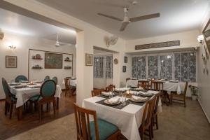 uma sala de jantar com mesas e cadeiras brancas em LohonoStays Homestead, Corbett em Ramnagar