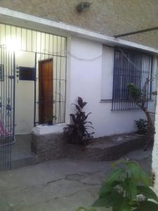 une maison blanche avec une porte et une clôture dans l'établissement Pousada do Alex, à Campos dos Goytacazes