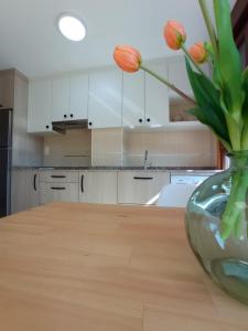 un jarrón de flores en una mesa de madera en una cocina en Apartamento Alfa, en Monforte de Lemos