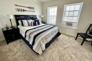 a bedroom with a bed and a chair and two windows at Sea La Vie Townhouse in Navarre