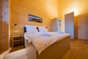 1 dormitorio con 1 cama grande y pared de madera en NETTEN Naturerlebnis Holz-Chalets en Daun