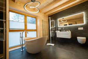 ein Badezimmer mit einer großen Badewanne und einem Waschbecken in der Unterkunft NETTEN Naturerlebnis Holz-Chalets in Daun