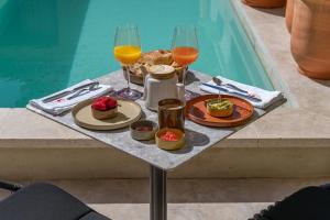 - un plateau de nourriture et de boissons sur une table à côté de la piscine dans l'établissement Marcelle en Camargue, à Aigues-Mortes