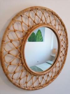 a mirror with a rattan frame on a wall at Studio apartman Cactus in Zagreb