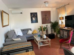 een woonkamer met een bank en een tafel bij Maison Avec jardin clôturé in LʼIsle-sur-la-Sorgue