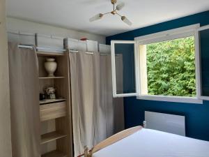 een slaapkamer met blauwe muren en een raam en een bed bij Maison Avec jardin clôturé in LʼIsle-sur-la-Sorgue