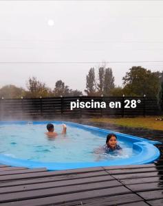 Dos personas están nadando en una piscina en Cabanas Chosco Alto, en Pucón