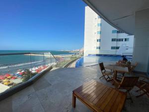 balcón con mesa, sillas y vistas al océano en Apartamento frente a la playa, en Cartagena de Indias