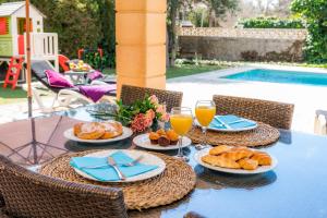 een tafel met borden brood en glazen sinaasappelsap bij Casa Arturo in Sa Coma
