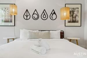 Un dormitorio con una cama blanca con toallas. en Picture-Perfect Trendy Vibes Minutes From Rainey, en Austin