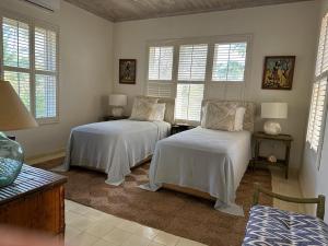 two beds in a room with two windows at Twin Coves House home in Governorʼs Harbour