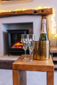 a bottle of champagne and two glasses on a table at Ava Lily Cottage, Tideswell in Tideswell