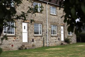 an old stone building with white doors and windows at Cliff Stud Retreat, Helmsley, Frankel Cottage in Helmsley
