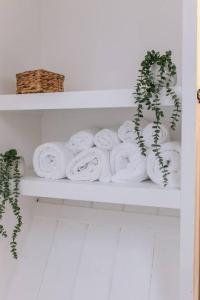 a shelf with a bunch of white towels and a plant at Ava Lily Cottage, Tideswell in Tideswell