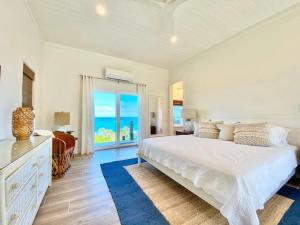 een witte slaapkamer met een bed en uitzicht op de oceaan bij Azure home in Palmetto Point