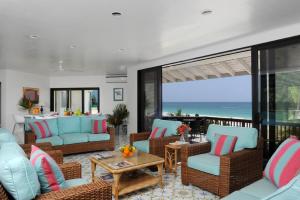uma sala de estar com sofás e cadeiras azuis e o oceano em Provender home em Savannah Sound