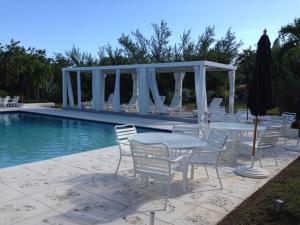 un grupo de mesas y sillas junto a una piscina en Provender home, en Savannah Sound