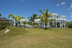 duży biały dom z palmami przed nim w obiekcie Miss Ruby home w Governor’s Harbour
