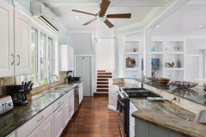 a kitchen with white cabinets and a ceiling fan at Sea Walk home in Governorʼs Harbour
