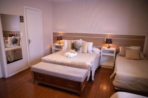 Habitación de hotel con 2 camas y 2 mesas en Hospedagem Vila Suiça Centro, en Gramado