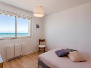 a bedroom with a bed and a window with the ocean at Apartment Les Mouettes by Interhome in Jullouville-les-Pins