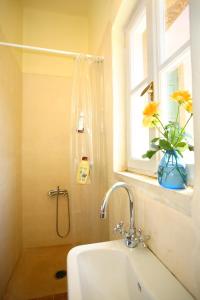 łazienka z umywalką i oknem oraz wazonem z kwiatami w obiekcie Villa Gallery Mania & Patrick Fabre w mieście Gerani
