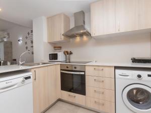 uma cozinha com armários brancos e uma máquina de lavar e secar roupa em Apartment Karma by Interhome em Segur de Calafell