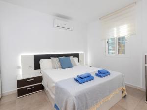 um quarto branco com 2 toalhas azuis numa cama em Apartment Karma by Interhome em Segur de Calafell