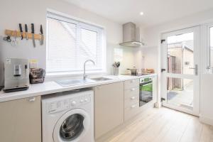 uma cozinha com uma máquina de lavar roupa e um lavatório em Elegant home mod kitchen, fast Wi-Fi, free parking em Carrickfergus