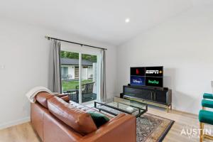 a living room with a leather couch and a tv at Insta-Ready Apartment in Barton Hills w King Bed in Austin