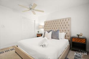 a bedroom with a large white bed with a ceiling fan at Great Clarksville Condo Near W 6th plus Free Parking in Austin