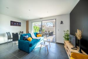 een woonkamer met een blauwe bank en een tafel bij La Pépite - Appt en Hypercentre au calme, Terrasse et Garage - Res Meyer in Royan