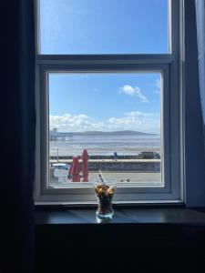 a window with a vase on a table looking out at the ocean at Bay view rooms at Mentone Hotel in Weston-super-Mare